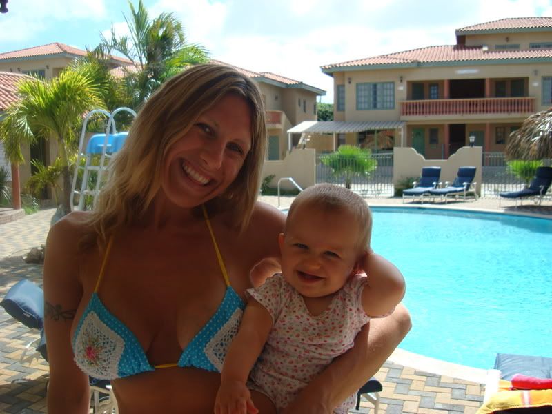 Woman holding young girl sitting poolside